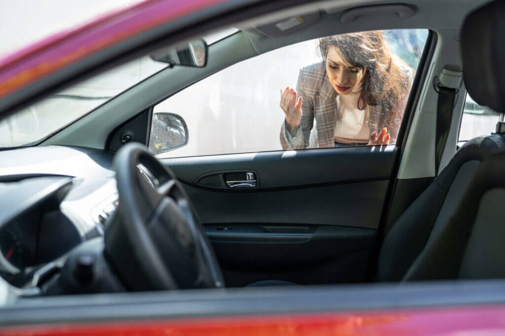 A person looking into a locked car with keys stuck inside it
