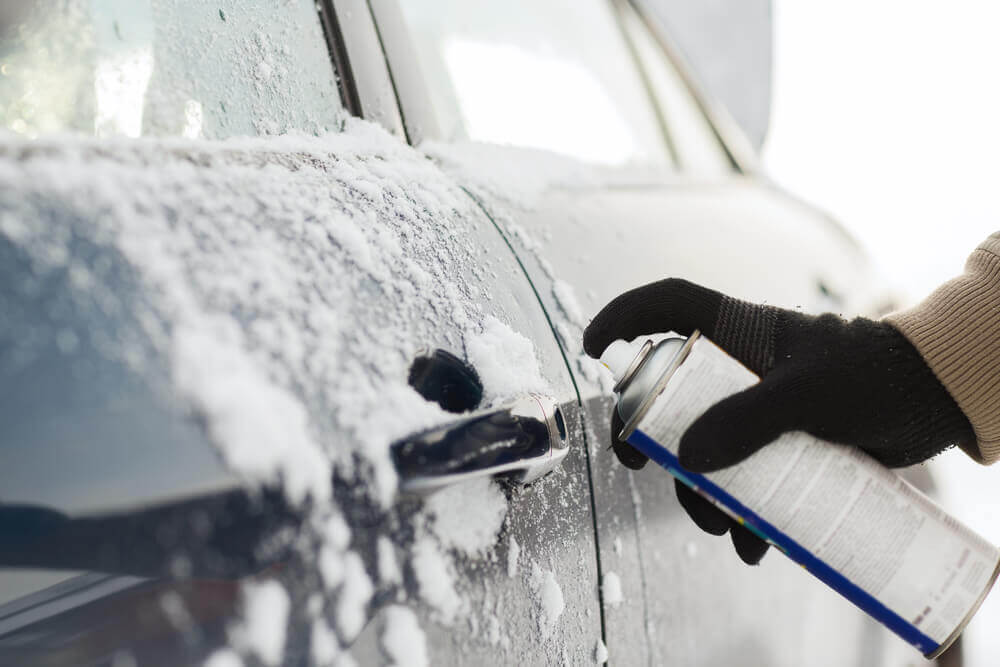 7 Tricks to Open A Frozen Car Door Lock You Might Not Know A Person Spraying Deicer On A Frozen Car Door Lock