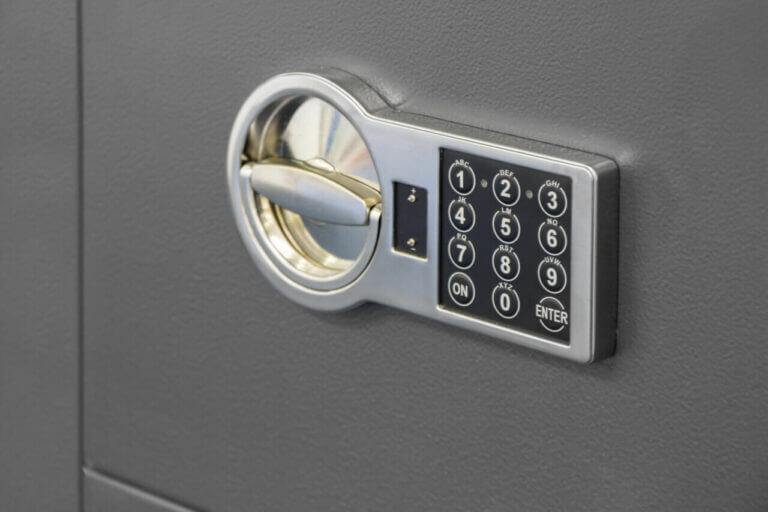 A close-up view of a digital safe lock crafted by a skilled locksmith. The lock features a numeric keypad with buttons numbered 0 to 9, along with additional function buttons: 'ON', 'CLEAR', and 'ENTER'. The handle and keypad are set in a metallic frame against a gray surface.
