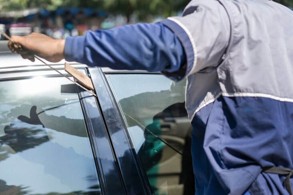 Locksmith to Unlock a Car: How Do Locksmiths Open Car Doors? Locksmith slipping a long tool through a car window