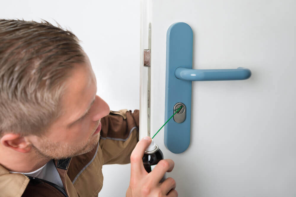 A Locksmith Lubricating The Keyhole