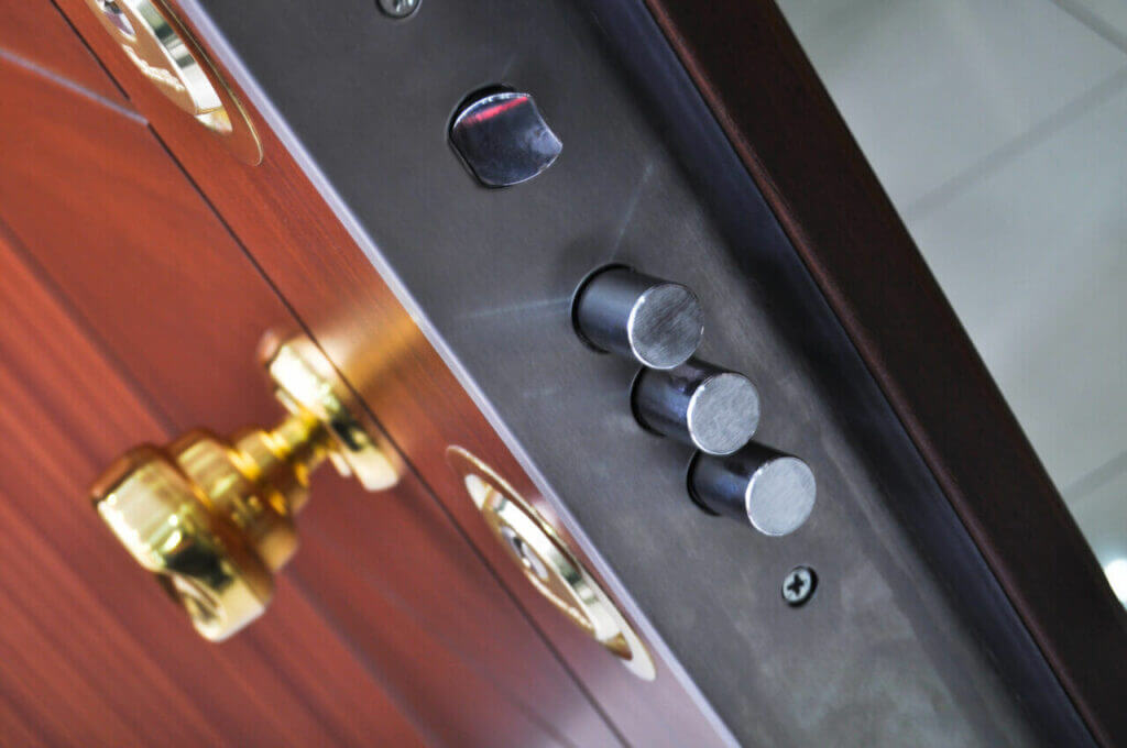 Close-up view of a door locking mechanism with three metal bolts and a keyhole, crafted meticulously by a locksmith. The door features a brass handle and a metallic striker plate, highlighting its secure locking features.